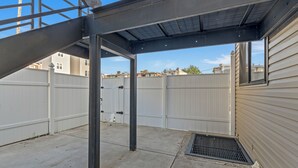 A covered outdoor area with a metal structure, a concrete floor, and a white fence. - Serenity Stays Charming 3bd 2.5ba Oasis (Philadelphia)