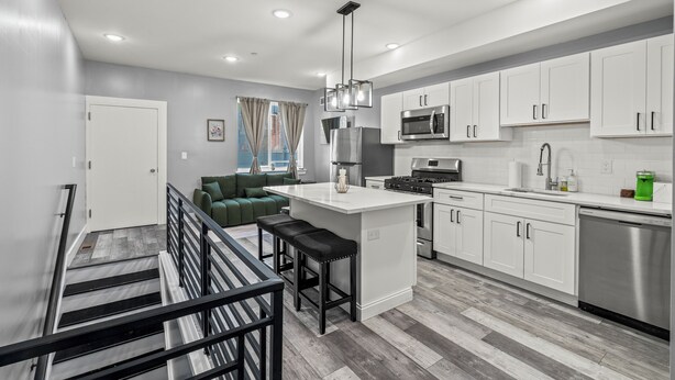 A modern kitchen with white cabinets, a stainless steel refrigerator, and a built-in microwave. - Serenity Stays Charming 3bd 2.5ba Oasis (Philadelphia)