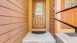 A wooden door with a glass panel, a doormat, and a concrete step leading to a staircase. - 1 Mi to Ponderosa State Park: Condo w/ Pool Access (McCall)
