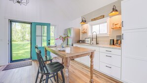 Een moderne keuken met een houten tafel, witte kasten en uitzicht op een groen gazon door de schuifdeur.
