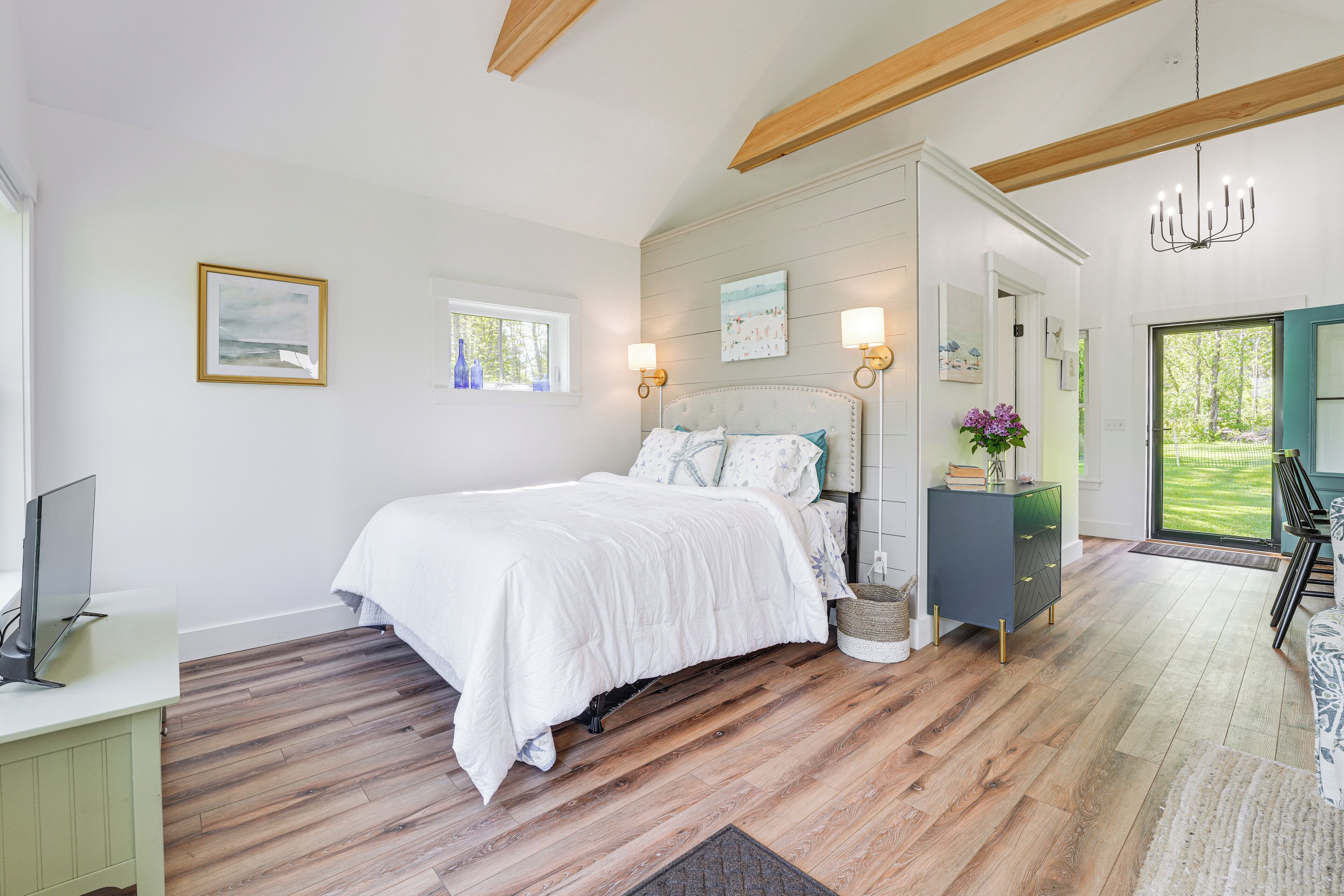 A bedroom with a bed, bedside table, and a desk with a computer.