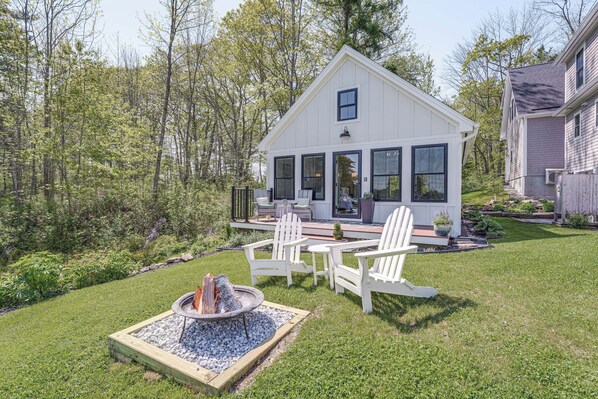 Une maison blanche dotée d’une terrasse, entourée d’une pelouse bien entretenue et d’arbres.