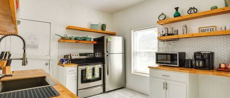 A modern kitchen with white cabinets, a stainless steel refrigerator, a microwave, and a coffee maker on the countertop.