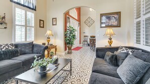 A living room with two sofas, a coffee table, and a potted plant. There is a window with curtains, a lamp, and a framed picture on the wall. - Golf, Fish & More: Cozy ‘Safari Unit’ in Atwater! (Atwater)