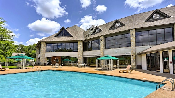 A large outdoor swimming pool with lounge chairs and umbrellas, surrounded by a building with large windows and stone pillars. - Pool & Lake Access: 'Cozy Nest' in Branson West (Branson West)