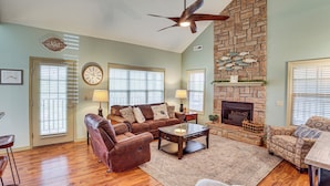 A living room with a fireplace, leather sofas, a coffee table, and a stone wall. - Pool & Lake Access: 'Cozy Nest' in Branson West (Branson West)