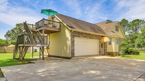 A two-story house with a garage, a balcony with a green umbrella, and a well-maintained lawn. - 10 Mi to Mobile Bay: Family Apt in Silverhill! (Silverhill)