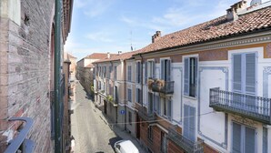Una calle estrecha con edificios tradicionales, una camioneta blanca estacionada al costado y un cielo azul despejado.