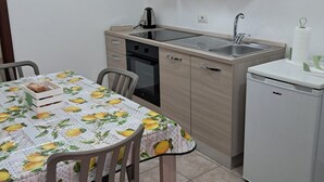 Una cocina compacta con una mesa de comedor, sillas, un lavamanos, una estufa y armarios.