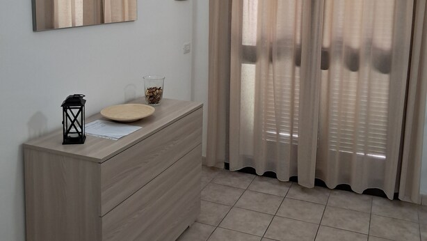 Un baño moderno con tocador de madera, un espejo, un farol negro y un recipiente de vidrio sobre el mostrador.