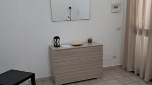 Una habitación minimalista con un aparador de madera, una mesita pequeña y un espejo colgado en la pared.