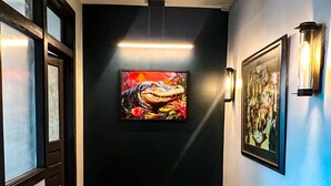 Un pasillo con suelo de madera, pared negra y dos obras de arte enmarcadas.