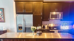 Una cocina con armarios de madera oscura, electrodomésticos de acero inoxidable y una isla central con taburetes de bar.