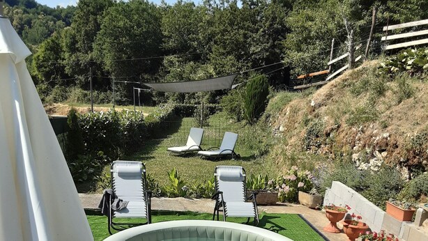 Ein Whirlpool, umgeben von Topfpflanzen und Gartenmöbeln.