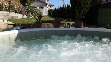A hot tub with water, surrounded by potted plants and a stone wall.