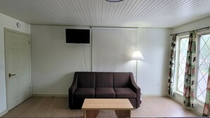 A room with a sofa, a small table, two beds, a TV, and a window with curtains. - 2 Bedroom Triple Queen Room - 2QQQS (Gatlinburg)
