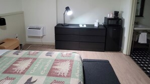 A bedroom with a bed, a desk, a dresser, a lamp, a heater, and a microwave. - 2 Bedroom Triple Queen Room - 2QQQS (Gatlinburg)