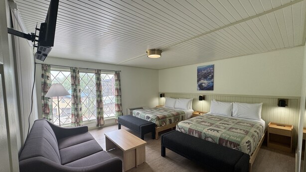 A hotel room with two beds, a sofa, a table, and a TV. - 2 Bedroom Triple Queen Room - 2QQQS (Gatlinburg)