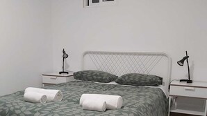 A bedroom with a bed, two bedside tables, a window, and a door. - Central Lisbon Terrace (Lisboa)