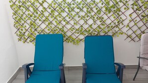 Two teal chairs with dark frames in a room with a tiled floor and a wall-mounted plant grid. - Central Lisbon Terrace (Lisboa)
