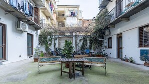 Une cour avec un banc et une table en bois, entourée de plantes en pot et de vélos.