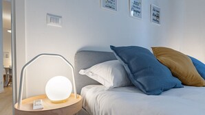 Un lit bien fait, avec des oreillers blancs et bleus, une table de chevet avec une lampe, et un mur orné de citations inspirantes encadrées.