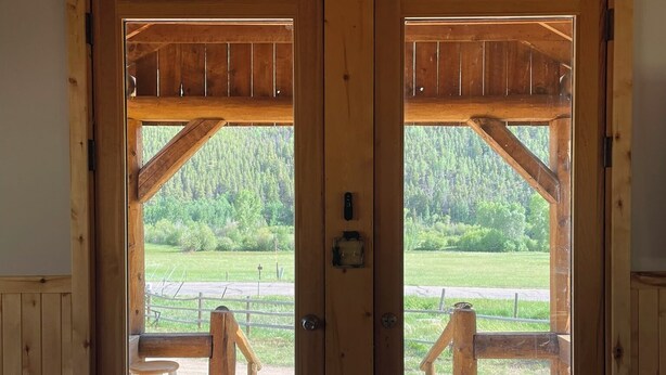A wooden cabin with a large door opening to a deck area.