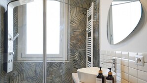 Une salle de bain avec une douche à parois de verre, un lavabo blanc et un miroir.