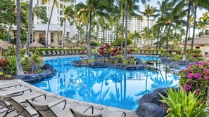 A resort pool area with lounge chairs, palm trees, and a reflection pool.