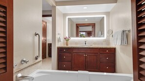 A modern bathroom with a large vanity, a bathtub, and a mirror above the sink.