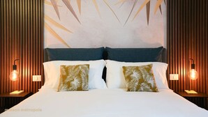 A hotel room with a large bed, two pillows with a leaf pattern, wooden paneling on the walls, and two bedside lamps. - Torino | Red Oasi Apartment (Torino)
