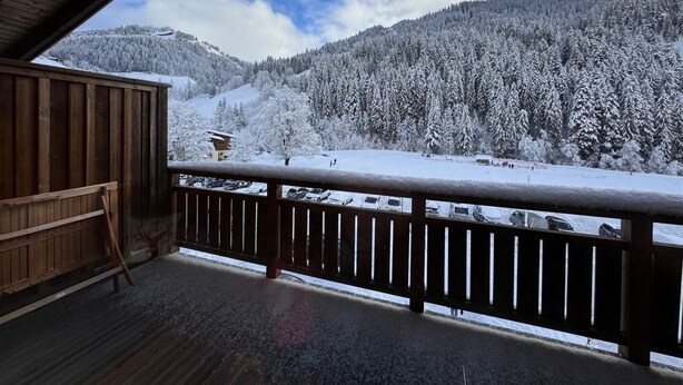 Un balcón de madera con vistas a un paisaje montañoso cubierto de nieve.