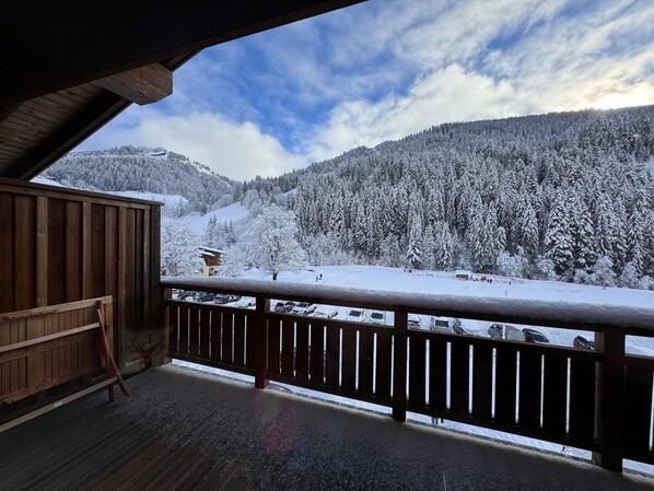 A wooden balcony with a view of a snow-covered mountain landscape.