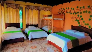 A room with four beds, a wooden bunk bed, a patterned floor, and curtains.