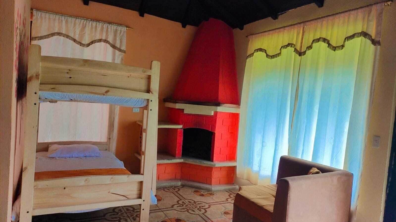 Una habitación con literas, chimenea y ventana con cortinas.