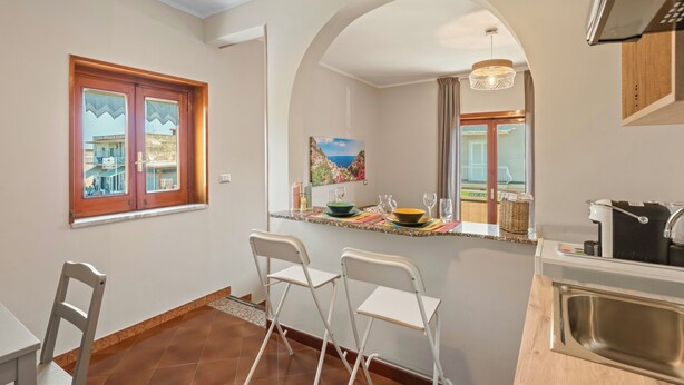 Cocina compacta con comedor, ventana con cortinas y vistas a un edificio.