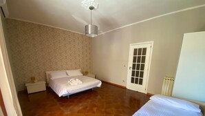 Un dormitorio con cama, mesita de noche, cómoda, puerta y radiador.
