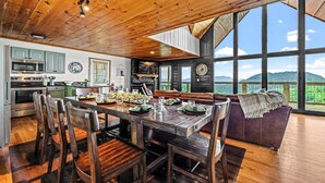 A spacious kitchen with a large dining table, wooden ceiling, and a view of mountains through large windows. - 6 Bedroom VIEW next to Dollywood FLASH SALE today (Sevierville)