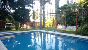 Une piscine avec un plongeoir métallique et un banc.