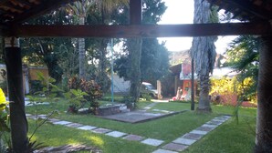 Un jardin avec un chemin pavé, des plantes en pot et une structure dotée d’un toit de chaume.