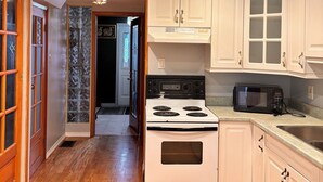 A kitchen with white cabinets, a stove, a microwave, and a sink. - A min walk to the zoo and University!2 bed apartment (Peterborough)