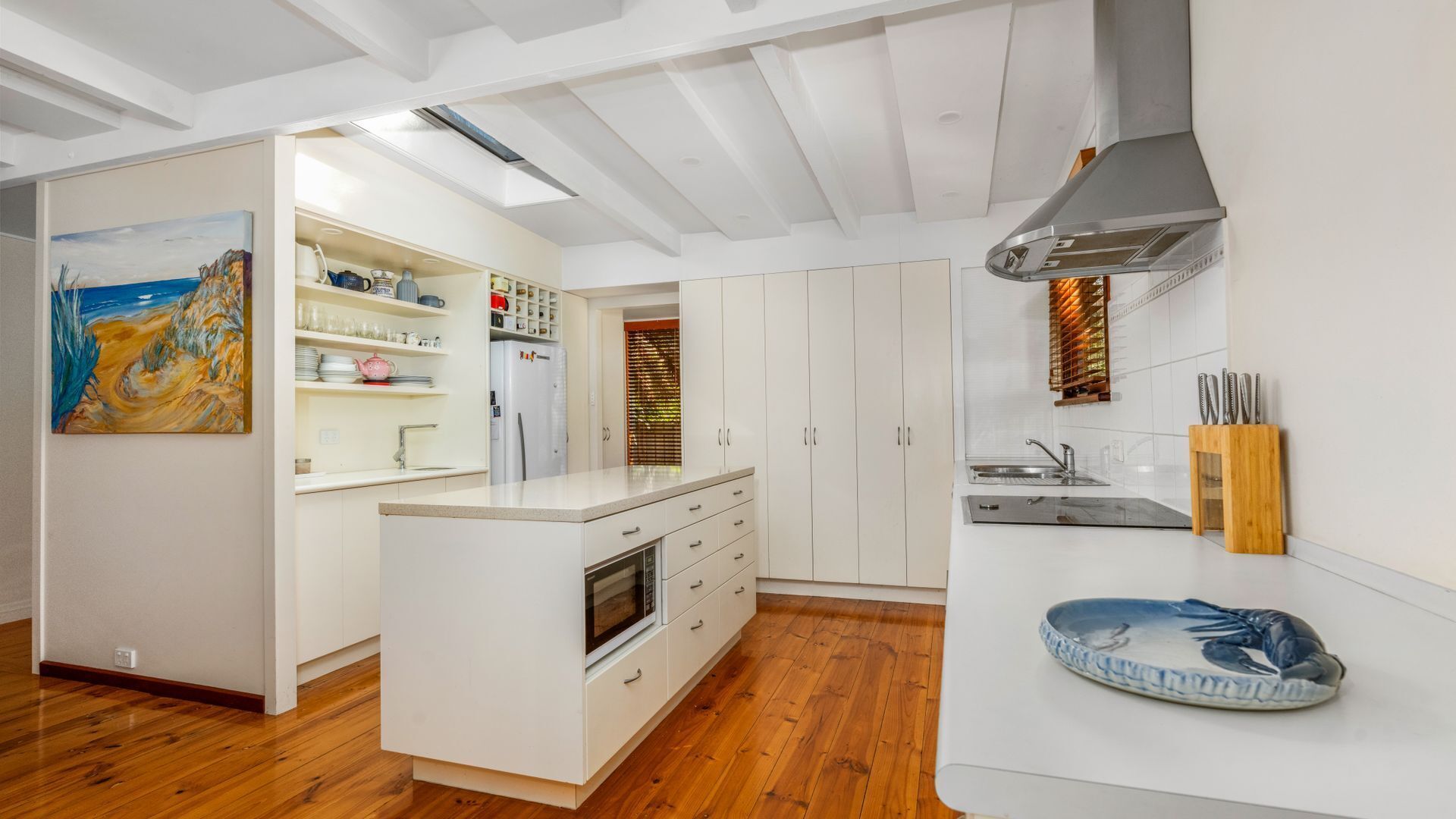Une cuisine moderne avec des meubles blancs, un îlot central et un four encastré.
