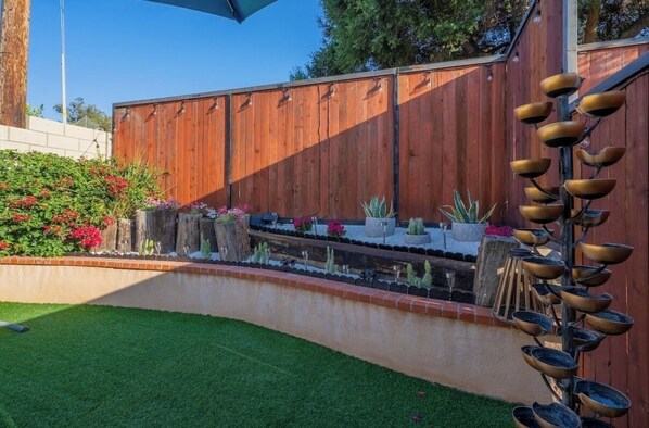 A wooden fence, a small garden with plants, and a metal sculpture.