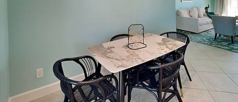 A dining area with a marble table and black wicker chairs, a ceiling fan, and a light blue wall.