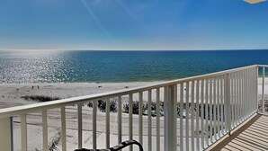 A balcony with a view of the beach and ocean.