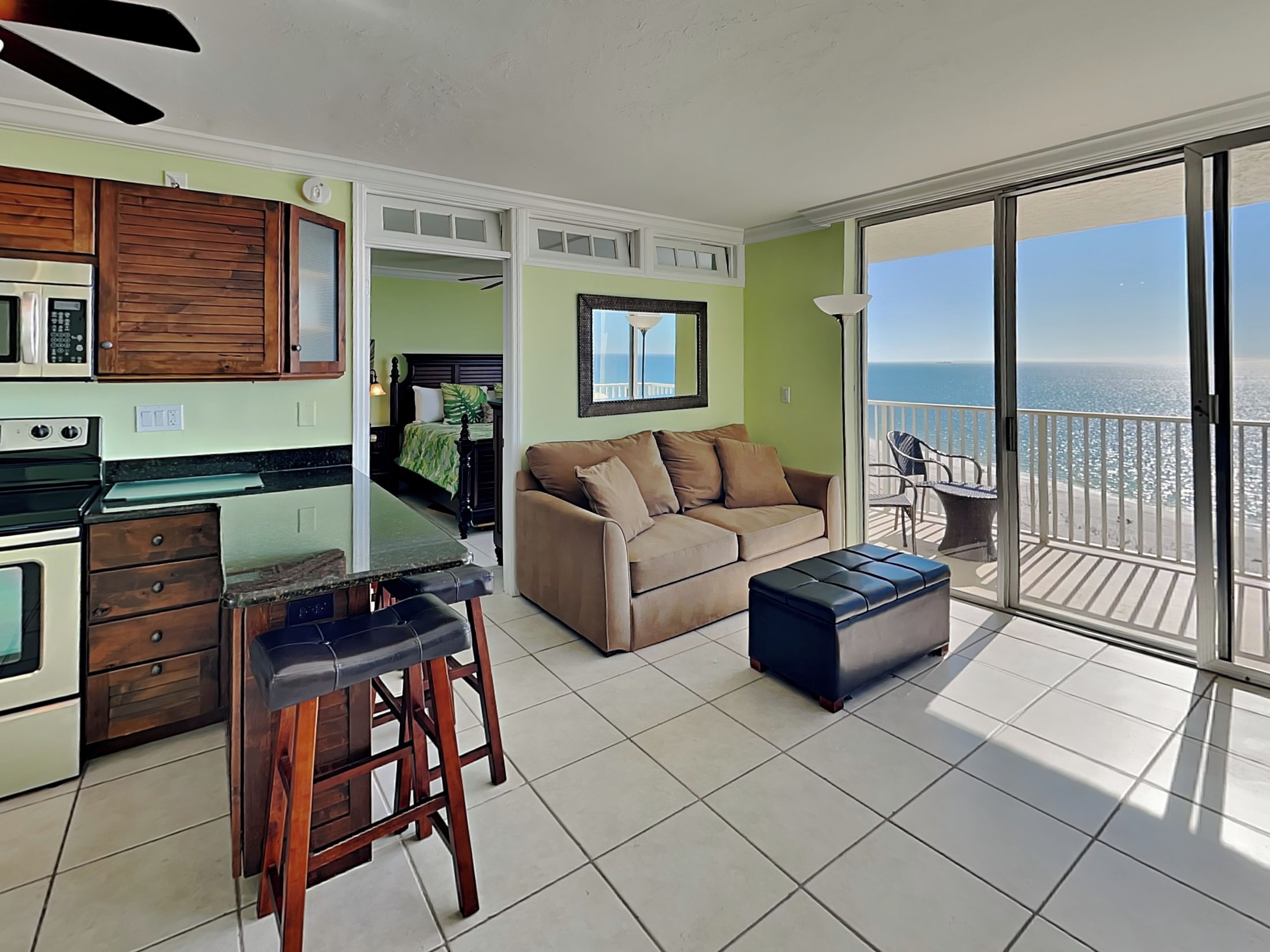 A modern living room with a kitchen, a balcony with a view of the ocean, and a dining area.
