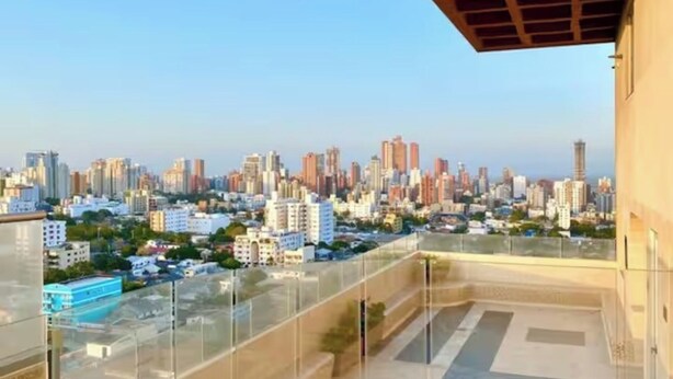 A cityscape view from a balcony with a clear sky. - Central Modern Duplex with Panoramic View (Unknown)