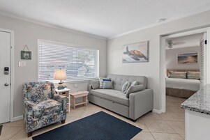 A living room with a grey sofa, patterned armchair, and a small side table with a lamp.