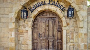 A stone arched entrance with a wooden door and two lanterns, labeled "Kemer Palace."
