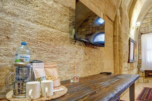 A rustic stone wall with a wooden table set with a water bottle, a thermos, and two white mugs.